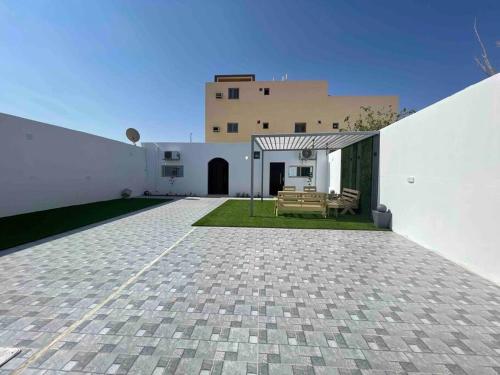 un patio de un edificio blanco con un pabellón en شاليه راقي بمسطحات خضراء وغرفة نوم, en Qufār