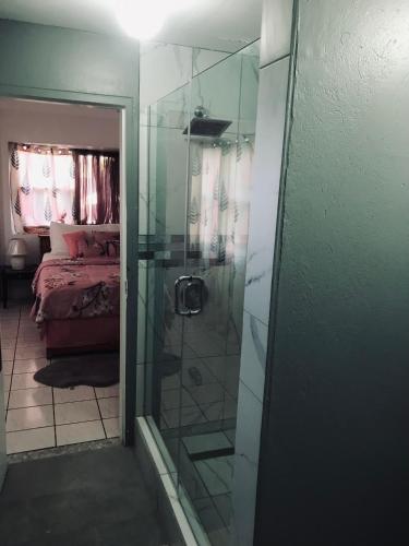 a bathroom with a shower with a glass door at HCEAS villa is 5 min fr. airport & to the beaches in Bon Accord