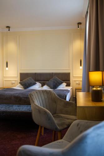 a hotel room with two beds and a chair at Hotel Maria Helena in Szczawno-Zdrój
