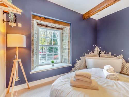 a bedroom with purple walls and a bed with a window at Deacons Apartment 2 - Uk45212 in Chapel en le Frith
