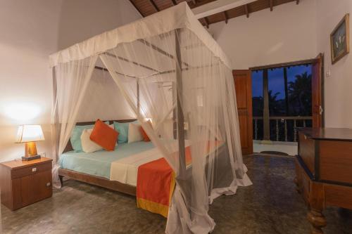 a bedroom with a bed with a canopy at Hotel Zeilan Sunset Point in Unawatuna