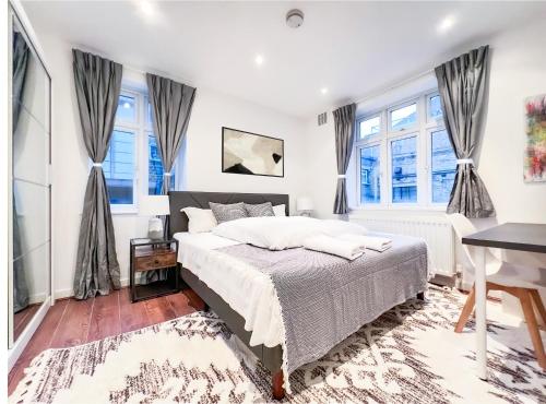 a bedroom with a bed and two windows at Central London Apartment Camden in London