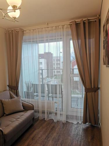 ein Wohnzimmer mit einem Sofa und einem großen Fenster in der Unterkunft EVARENT Buto nuoma Birštone in Birštonas