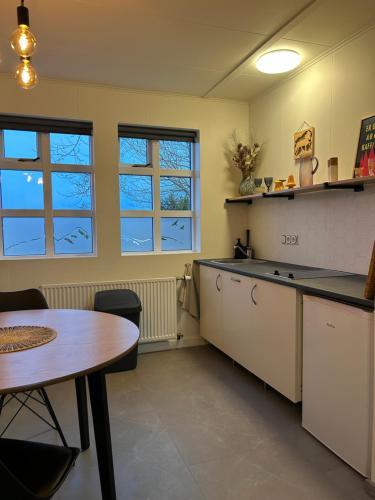 a kitchen with a table and a table and some windows at Cozy Bungalow in Reykjavík