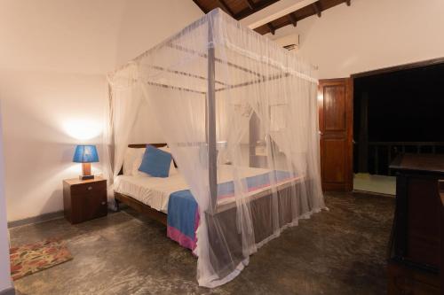 a bedroom with a canopy bed with white drapes at Hotel Zeilan Sunset Point in Unawatuna