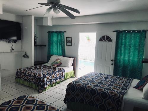 a bedroom with two beds and a ceiling fan at HCeas Villa Compound is 5 minutes from the airport and beaches, can sleep up to 30 ppl in Bon Accord