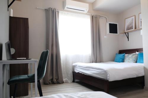 1 dormitorio con 2 camas y ventana con silla en Boutique City Hideaway Cebu Modern 2-Bedroom Condo Near IT Park, en Cebú
