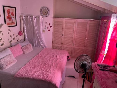 a bedroom with a pink bed and a fan at Home In Gated Community 24Hr Security And Wifi in Old Harbour