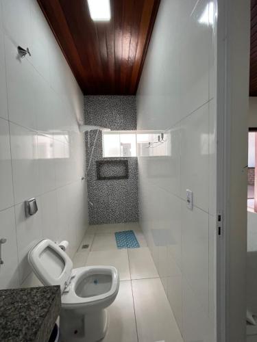 a white bathroom with a toilet and a sink at TROPICAL LAZER E EVENTOS - Casa em Lucas do Rio Verde in Lucas do Rio Verde