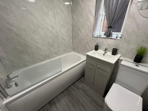 a bathroom with a tub and a toilet and a sink at Lingfield House - Spacious 3 Bed Detached Home From Home in Burton upon Trent