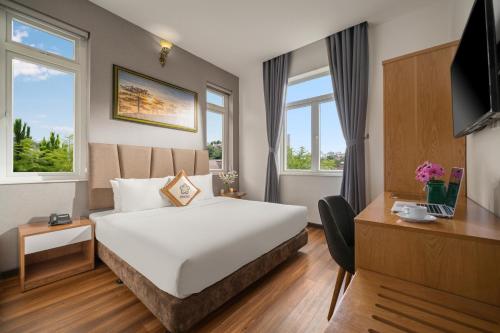 a hotel room with a bed and a desk and windows at Myrtle Boutique Hotel in Da Lat