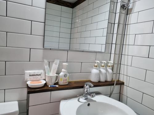 La salle de bains est pourvue de carrelage blanc, d'un lavabo et d'un miroir. dans l'établissement Wonhwaroo, à Gyeongju