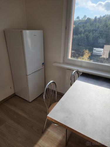 a kitchen with a refrigerator and a table and a window at xxxxxx in Banská Bystrica