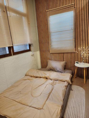 a bed in a room with a table and two windows at 205Homely Private room in apartment Near BTS KU St in Ban Yang