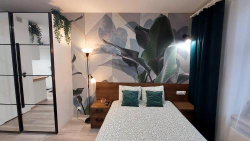 a bedroom with a bed with a plant mural on the wall at theApartments Gdańska in Łódź