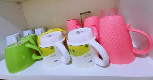 a group of cups and mugs sitting on a shelf at Legoland-4mins Walk-Spacious-Kids Friendly with Bathtub@ Happy Travel- AFINITY RESIDENCY in Nusajaya