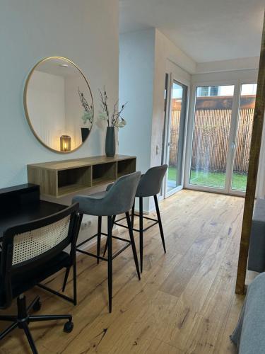 Zimmer mit einem Spiegel, einem Schreibtisch und Stühlen in der Unterkunft Moderne Erdgeschosswohnung in Augsburg