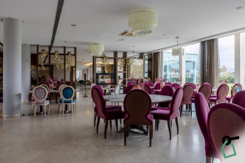 a dining room with purple chairs and tables in a restaurant at HOTIDAY Hotel Pisa in Pisa