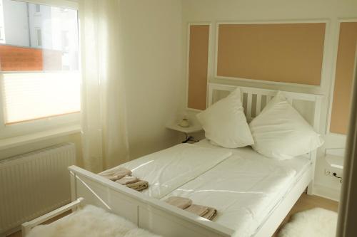 uma cama branca com almofadas e uma janela num quarto em Wohnen am Bahnhof em Lübeck
