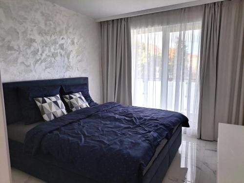 a bedroom with a blue bed and a large window at Tabáň Luxury apartment (city center & free parking) in Nitra