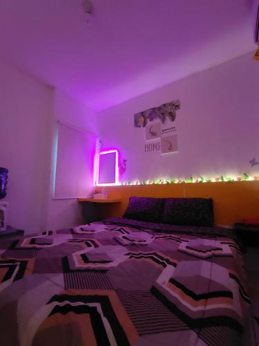 a bedroom with a bed with a purple lighting at RDTROOM At Aeropolis in Teko