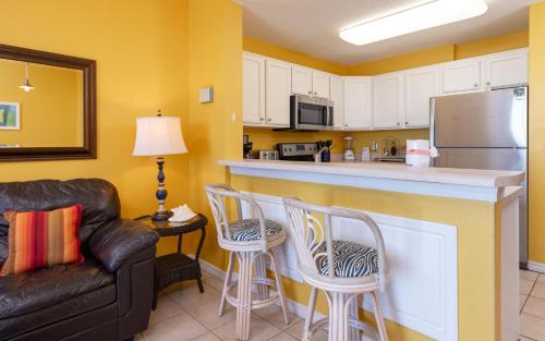 a kitchen with a bar with two chairs and a couch at The Dunes 503 condo in Gulf Shores