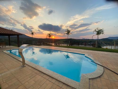 a large swimming pool with a sunset in the background at Rancho Chega Mais 2 in Carmo do Rio Claro