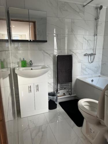 a white bathroom with a sink and a toilet at Luton Home near Airport Private & Shared Bathroom Option in Luton