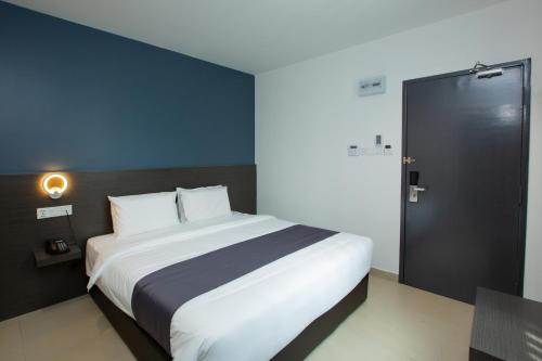 a bedroom with a large white bed and a black door at 1 Hotel Signature in Port Dickson