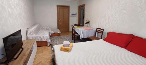 ein Zimmer mit einem Bett, einem Fernseher und einem Tisch in der Unterkunft Двухкомнатная квартира на Арбате in Almaty