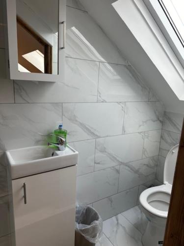 a white bathroom with a toilet and a sink at Luton Home near Airport Private & Shared Bathroom Option in Luton