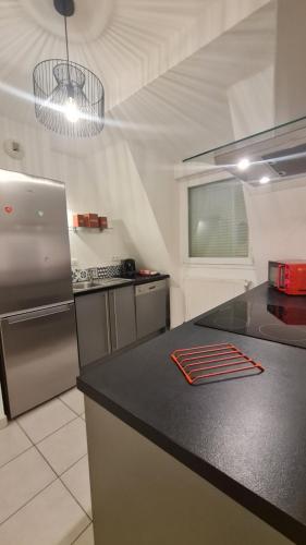 Il comprend une cuisine équipée d'un comptoir noir et d'un réfrigérateur. dans l'établissement Logement entier : appartement, Houssen, à Houssen