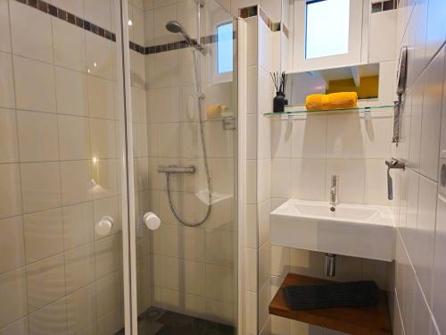 ein weißes Bad mit einer Dusche und einem Waschbecken in der Unterkunft Vrijstaand vakantiehuis AK14 Aagtekerke in Aagtekerke