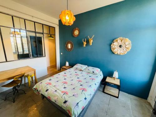 - une chambre avec un lit, un bureau et un mur bleu dans l'établissement Appartement climatisé 50m2 une chambre proche centre et gare, à Montpellier