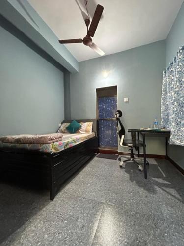 a bedroom with a bed and a desk and a ceiling fan at Shobha Niwas in Nandgaon