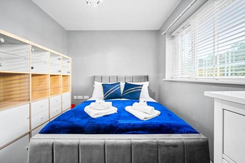a bedroom with a blue bed with towels on it at 3 Bed Family House in Solihull ☆ LARGE GARDEN & FREE PARKING ✪ BY (BHX) Birmingham Airport → (NEC) National Exhibition Centre, Resorts World Birmingham, Jaguar Land Rover Solihull - BY PILOT MY PROPERTY ® in Water Orton