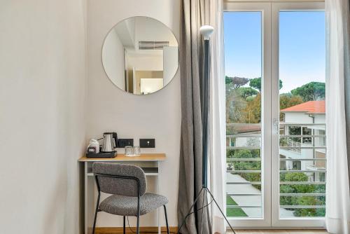 a mirror and a chair in a room with a window at Resort Miramonti in Forte dei Marmi
