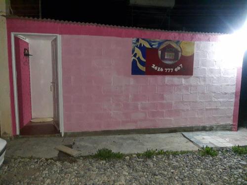 a pink brick wall with a door and a sign at dormi La familia in Malargüe