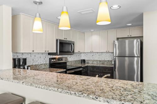 a kitchen with white cabinets and a stainless steel refrigerator at Seaside Resort in Myrtle Beach