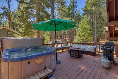 a hot tub on a deck with an umbrella at Tahoe Woods by Tahoe Getaways - Pet Friendly Tahoe Park Cabin w Hot Tub, Fireplace, Near Skiing! in Tahoe City