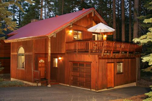 a large wooden cabin with a balcony and an umbrella at Tahoe Woods by Tahoe Getaways - Pet Friendly Tahoe Park Cabin w Hot Tub, Fireplace, Near Skiing! in Tahoe City