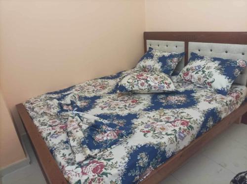 a bed with a floral comforter and pillows on it at L’oranais in Oran