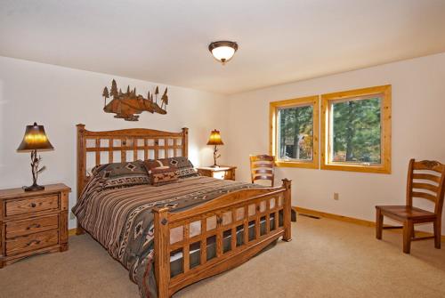 um quarto com uma grande cama de madeira e 2 cadeiras em Valley View at Palisades -4 BR w Mountain Views, Pet-Friendly, and Close to Village em Olympic Valley