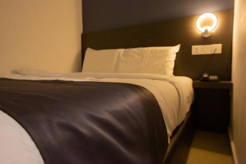 uma cama num quarto de hotel com uma luz na parede em 1 Hotel Signature em Porto Dickson
