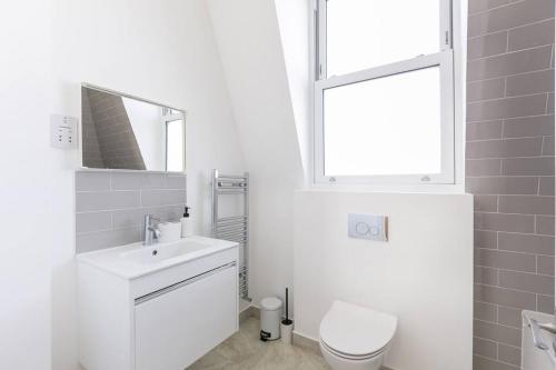 a white bathroom with a sink and a toilet at Stunning S/Wimbledon Flat w/parking in London, Uk in London