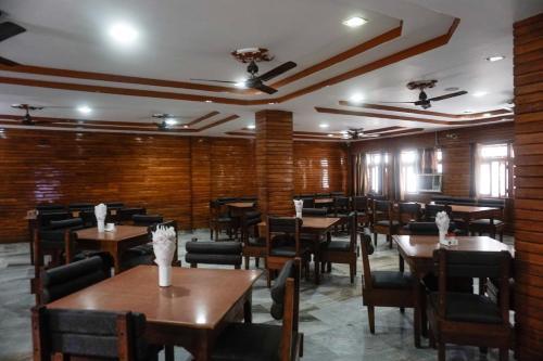 a dining room with wooden tables and chairs at The Avantika Hotel & Woodland Restaurant in Gorakhpur