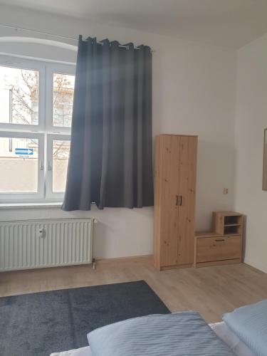 a bedroom with a blue curtain and a wooden cabinet at Zur Altstadt in Plauen