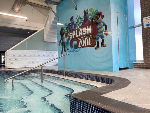 a swimming pool with a mural on the wall at Lyons Robin Hood Holiday Park - Private Caravans with PS5 and WiFi in Meliden