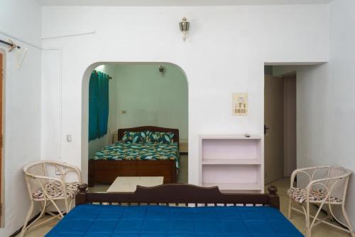 een slaapkamer met een bed, 2 stoelen en een spiegel bij Kadal Homestay in Pondicherry