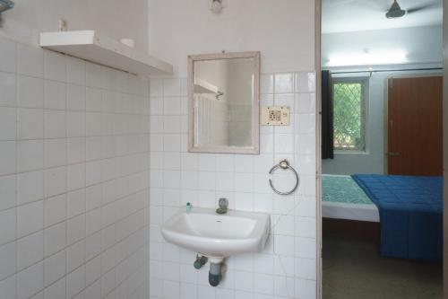 een badkamer met een wastafel, een spiegel en een bad bij Kadal Homestay in Pondicherry